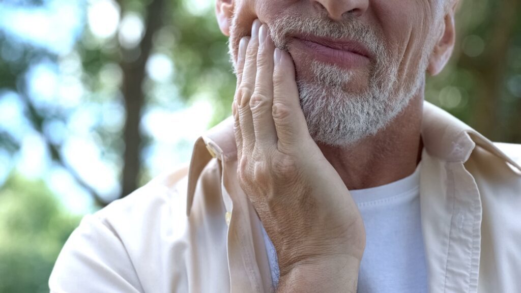 Closeup of man experiencing jaw soreness