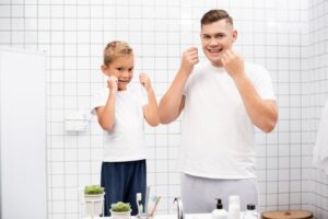 father son cleaning teeth floss