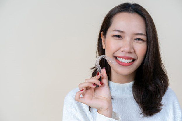 Woman holding her Invisalign tray in her hand.
