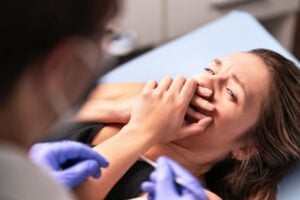 woman covering her mouth in fear that getting a dental crown can hurt