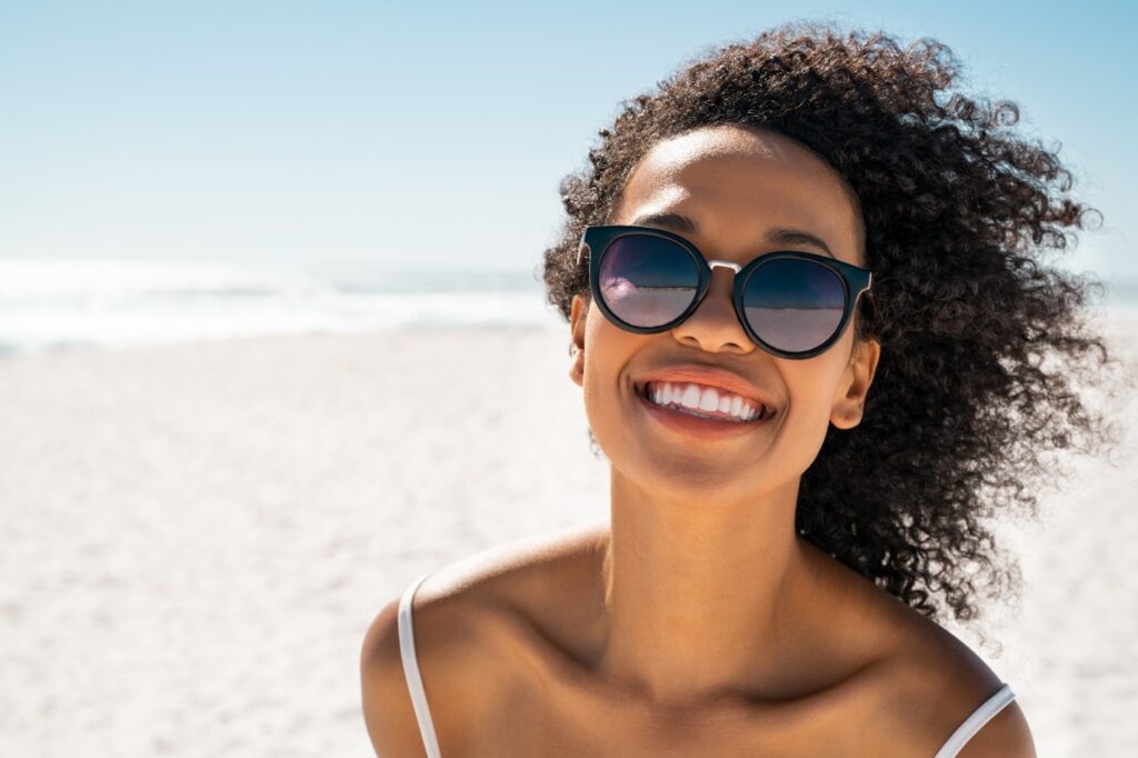 person who underwent cosmetic dental treatments smiling on beach