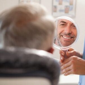 A man happily looking at his healthy teeth after an anxiety-free dental visit.