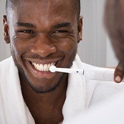 Man Brushing his teeth preventing the need for emergency dentistry