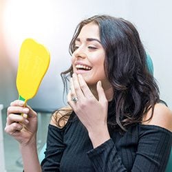 Woman inspecting teeth after Emergency Dentistry Appointment