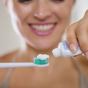 Woman Brushing teeth after tooth Extraction in Dallas, TX