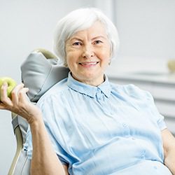 older woman holding an apple to eat with new implants