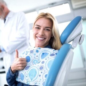 A woman smiling while giving a thumb's up after getting porcelain veneers in Dallas.