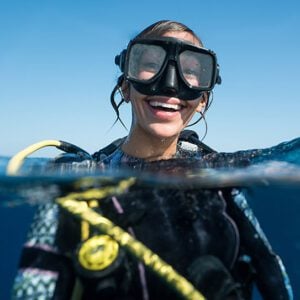 A young woman smiling on scuba diving vacation with recently whitened teeth.