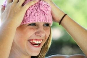 A young girl in a pink hat, smiling after a regular dental checkup in Dallas.