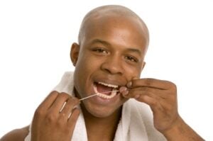 A man flossing to prevent costly gum disease in Richardson.