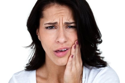 A woman clutching her jaw in need of a root canal in Richardson.