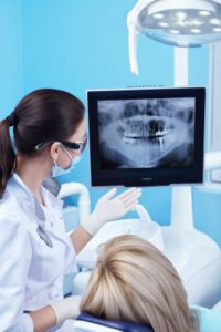 A dentist examining a jawbone X-ray with a patient.