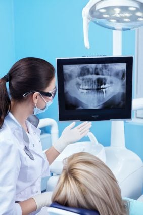 A dentist examining a jawbone X-ray with a patient.